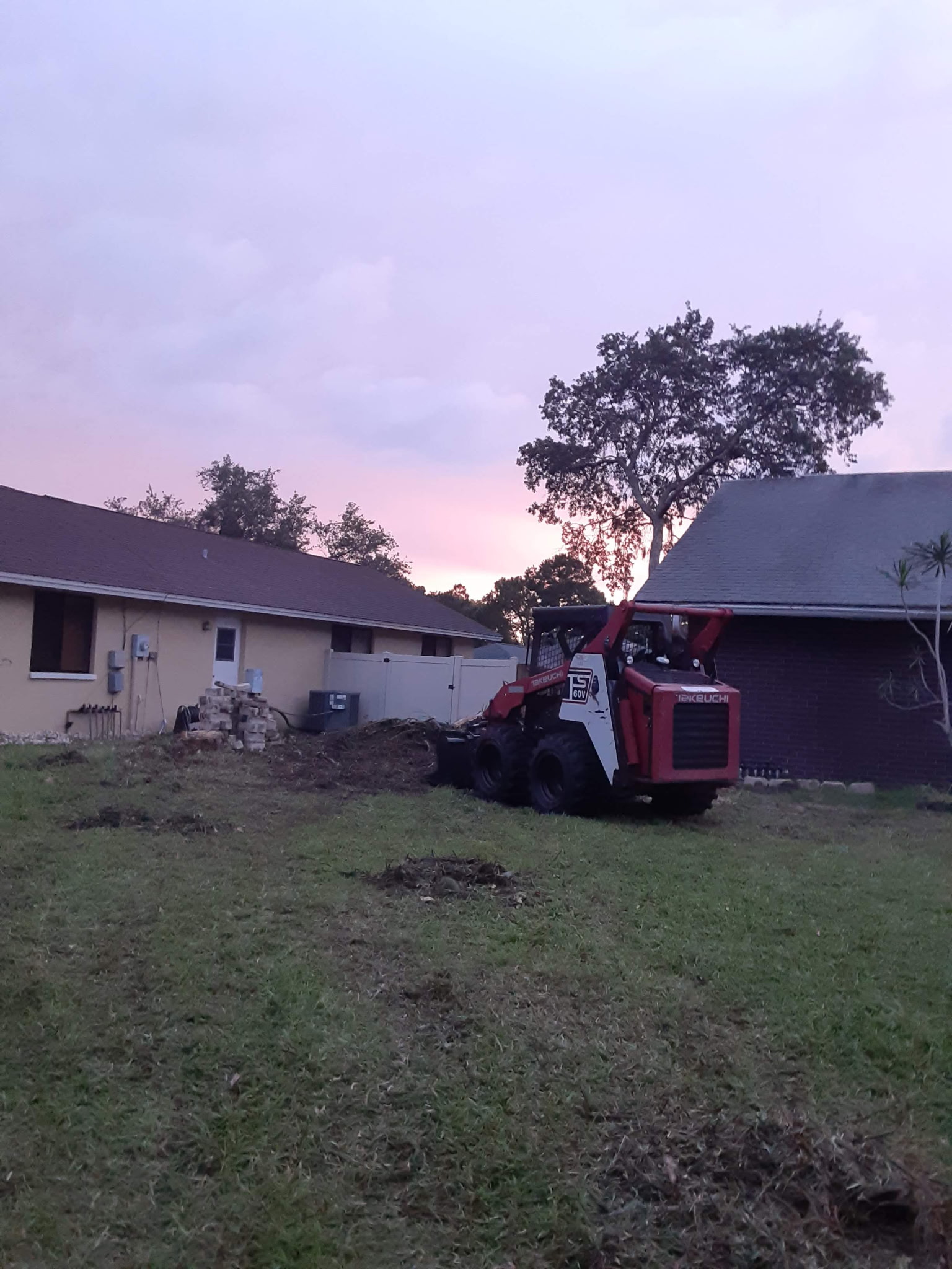 Machine-assisted yard cleanup at sunset
